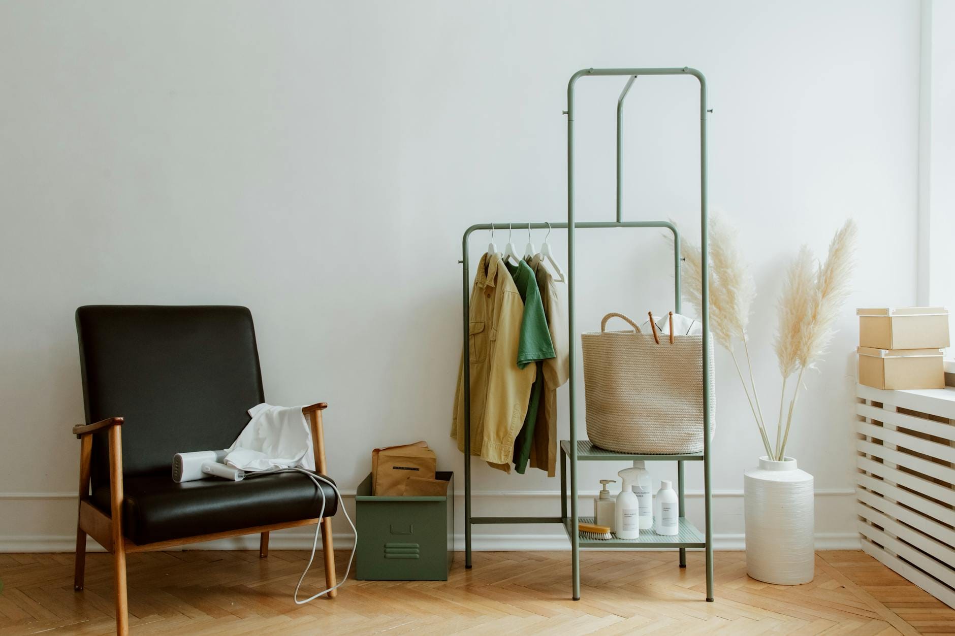 A modern home corner with a leather armchair, clothing rack, and decorative elements.